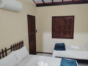 a room with two beds and a door at Boipeba Encantos in Ilha de Boipeba