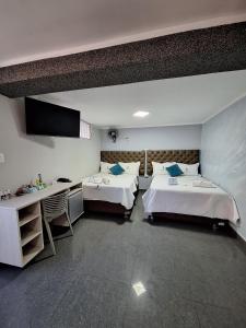 ChepénHotel Jose Ignacio Chepen的一间卧室配有两张床、一张桌子和一台电视。