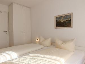 a white bedroom with two beds and a painting on the wall at 2-Raum FeWo Hüttenzauber - Hallenbad & Sauna in Fischen +7 photos