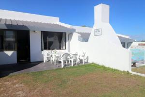 a white house with a table and chairs at The Gift Arniston in Arniston