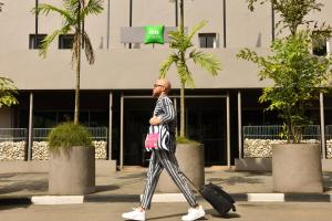 阿比让Ibis Styles Abidjan Plateau的带着手提箱走在街上的人