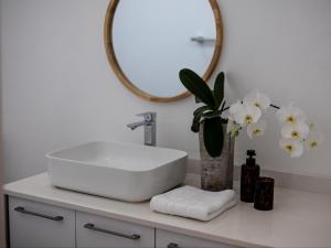 bagno con lavandino, specchio e fiori di Zonnekus Guesthouse a Città del Capo