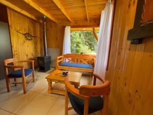 a room with a table and a bed and a stove at Valle de los Volcanes Lodge in Villarrica