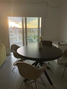 a dining room with a table and chairs and a window at Oroklini's Flat in Larnaka