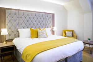 a bedroom with a large bed with yellow and blue pillows at Walton View Hotel in Drighlington