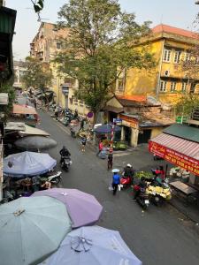 a city street with people on motorcycles and umbrellas at Sunny Balcony in Hanoi