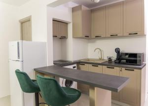 a kitchen with a counter and two green chairs at Urban Retreat in Onești