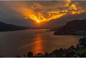 a sunset over a river with the sun setting at Ferienwohnungen Klinar in Millstatt