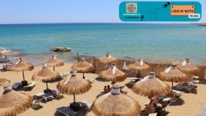a group of straw umbrellas and chairs on a beach at Noto Barocca - HolidayHome in Noto
