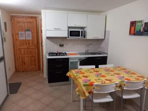 a kitchen with a table with chairs and a microwave at La casa di Teresa in Pragelato
