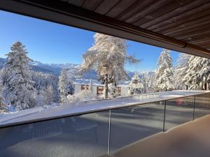 a view from the balcony of a house with snow covered trees at Renovated Mountain View Apartment - Les Eperviers in Crans-Montana