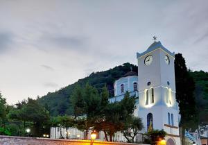 a white clock tower in front of a building at Villa Malila in Panagia