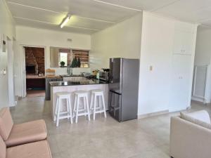 a kitchen with a refrigerator and a counter with bar stools at Hello Home Struisbaai in Struisbaai