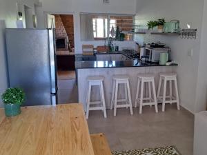 Una cocina con una encimera con taburetes y un refrigerador. en Hello Home Struisbaai, en Struisbaai 9 fotos más
