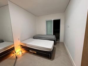 two twin beds in a room with a mirror at Vista Panorâmica Enseada in Guarujá +11 photos