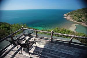 a table and two chairs sitting on a deck overlooking the ocean at Phangan Utopia Resort in Mae Haad