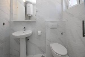 a white bathroom with a toilet and a sink at House Lavanda - Kricin, underground level apartment in Baška +14 photos
