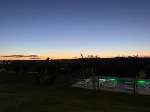 een zonsondergang boven een tuin met stoelen en een zwembad bij Cabañas AdamiS 5 in Villa Cura Brochero