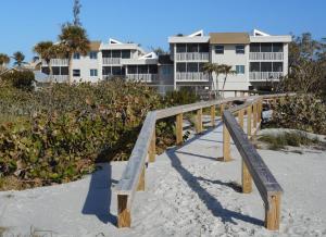 萨尼贝尔Shell Island Beach Club的海滩上的木桥,后面有建筑