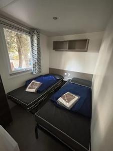 deux lits dans une petite pièce avec une fenêtre dans l'établissement Bonne Anse Plage 409 Mobile home 3 chambres 7 personnes, aux Mathes