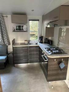 une petite cuisine avec une cuisinière et un évier dans l'établissement Bonne Anse Plage 409 Mobile home 3 chambres 7 personnes, aux Mathes
