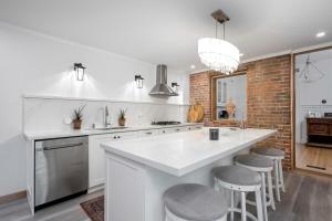 a kitchen with a large white counter and stools at 3bed 2bath heritage duplex - Prime Location in Collingwood