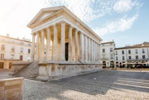 un temple avec des colonnes sur une place dans un bâtiment dans l'établissement Maison climatisée Gare à 10 min, idéale familles MaisonCarréeConciergerie, à Nîmes