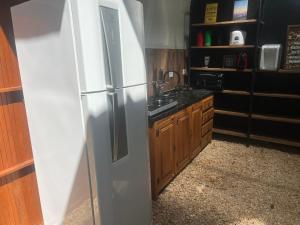 a kitchen with a refrigerator and wooden cabinets at Casa Fiji - Suites Luxo - Praia de Itamambuca - Ao lado da praia in Ubatuba