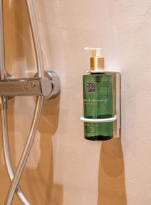 a green bottle of soap is hanging on a wall at Hôtel De Londres in Menton