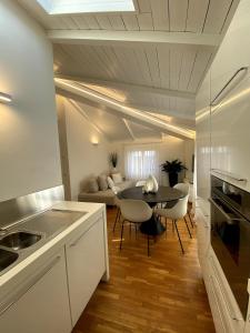 a kitchen and living room with a table and chairs at Grenier Blanc2 Elegante Mansarda 3 camere 5 ospiti in San Vicenzo di Galliera