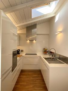 a kitchen with white cabinets and a sink and a skylight at Grenier Blanc2 Elegante Mansarda 3 camere 5 ospiti in San Vicenzo di Galliera +42 photos