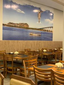 un restaurante con mesas de madera y una pintura de una persona saltando en Hotel Grutta, en Bom Jesus da Lapa