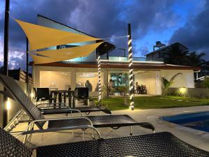 a house with a patio with chairs and a pool at Pousada Ondas do Mar in Porto De Galinhas