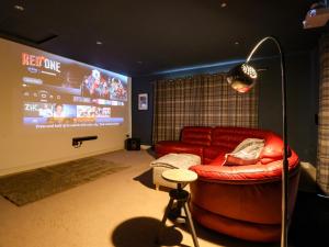a living room with a red couch and a big screen at The Pines in Skipton