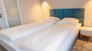 a large bed with white sheets and a blue headboard at VacationClub - Baltin Apartament 21 in Mielenko