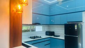 a kitchen with blue cabinets and a black refrigerator at Grace Villa Homestay, Cherupuzha in Peringom
