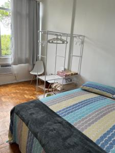 a bedroom with a bed and a chair and a window at Praia de Botafogo vista Pão de Açúcar in Rio de Janeiro