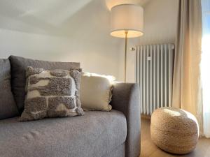 a living room with a gray couch with a pillow at Apartment mit Titisee-Blick - Villa Hubertus in Feldberg