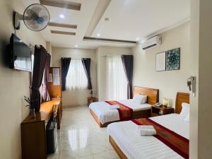 a hotel room with two beds and a flat screen tv at The Sun Hotel in Long Bình
