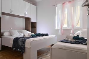 a white bedroom with two beds and a window at Vila Maričić in Sveti Petar