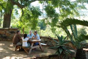 a group of people sitting at a picnic table at Down Gran's Self-Catering Cottage in Lobamba