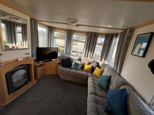a living room with a couch and a television at Long Beach Park Caravan, Hembsy in Great Yarmouth +7 photos