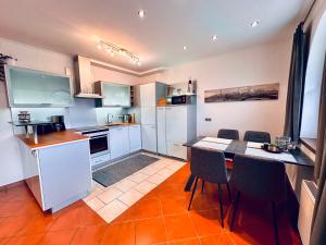a kitchen with white cabinets and a table and chairs at Appartement Treffhour in Ellmau