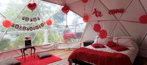 a room with a bed in a tent with red hearts at Glamping Eco Azulejo in Arbeláez