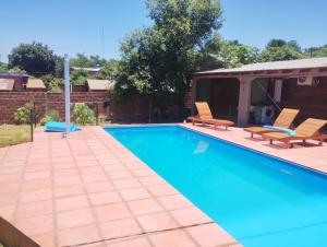 a swimming pool with two chairs and a house at 7copas in Puerto Iguazú
