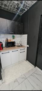 Una cocina con gabinetes blancos y un fregadero. en Garsoniera - moderna - Timișoara, en Timisoara 17 fotos más