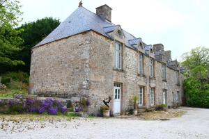 CarnevilleにあるGite du Manoir des Anoteuxの花の前に建つ古い石造りの建物