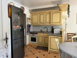 a kitchen with yellow cabinets and a black refrigerator at Le Noisetier in Cavalaire-sur-Mer