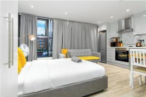 a bedroom with a large white bed and a kitchen at Shoreditch Studios by Keyhol Let in London