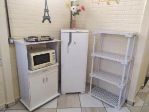 a kitchen with a refrigerator and a microwave on a shelf at Pousada - Flat - Kitnet - Mobiliada, Confortável e Perto de Tudo in Atibaia